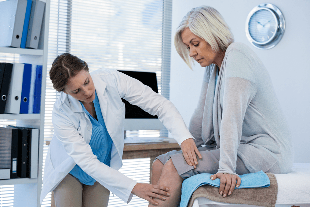 The doctor examines a patient with osteoarthritis of the knee joint